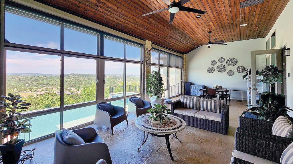 Spacious three-season patio enclosure with panoramic energy-efficient windows, wicker furniture, and wood-paneled ceiling in a San Antonio, Texas home
