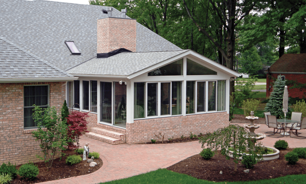 Brick home remodel in Cleveland featuring a large sunroom addition with energy-efficient windows and a landscaped patio area